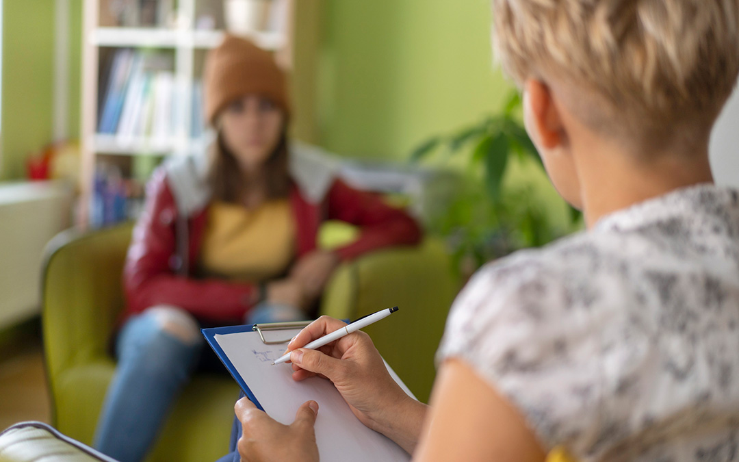 A certified mental health counselor talking with a teenager during a therapy session about substance use and making safe choices