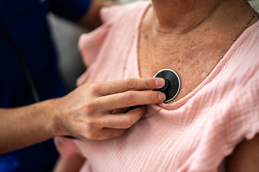 Older woman with heart disease with stethoscope on her heart