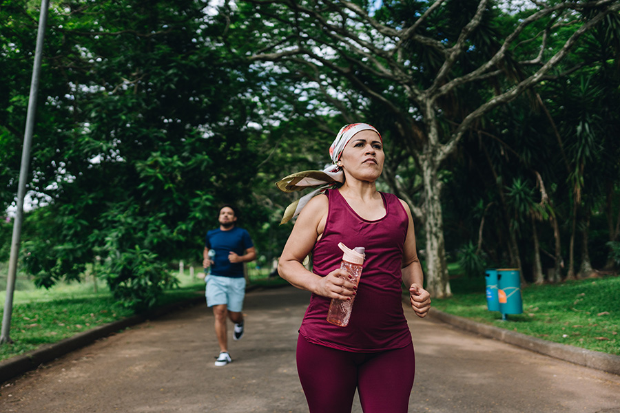 Cancer survivor jogging outdoors with a water bottle, showing strength and vitality through movement