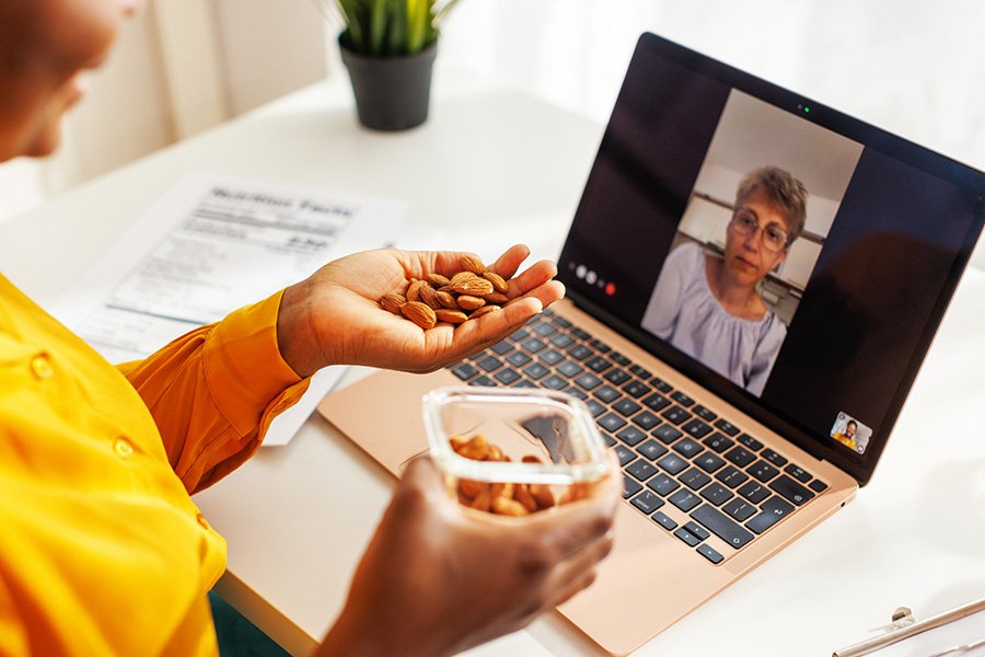 Female nutritionist shows to her client what is ideal serving size of nuts. They are talking over video call.